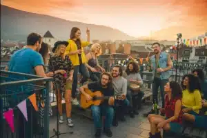 Travel Trends for Gen Z in 2026 2 Diverse Gen Z travelers laughing on a rooftop at sunset playing music