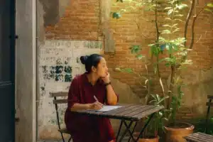 Pros and Cons of Solo vs Group Travel: What’s Right for You? 3 Solo traveler writing in a journal with at a cafe