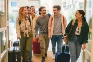 Pros and Cons of Solo vs Group Travel: What’s Right for You? 7 young travelers with luggage chinking in a hostel